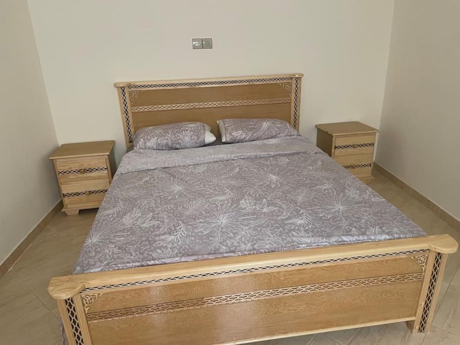un letto in legno con due cuscini sopra in una camera da letto di Een mooie familie appartement a Aït Farts