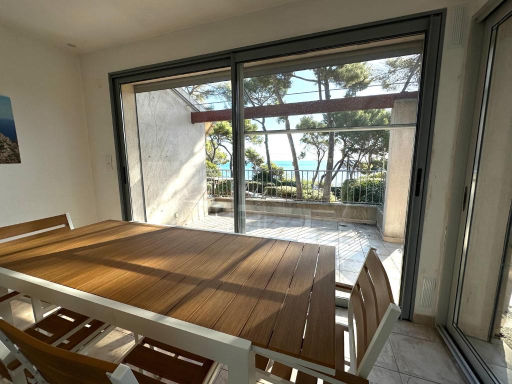 ein Esszimmer mit einem Holztisch und einem großen Fenster in der Unterkunft Grande villa face à la plage, superbe vue mer in La Seyne-sur-Mer