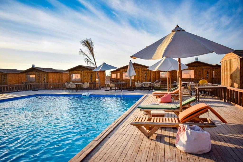 a swimming pool with chairs and an umbrella at Safy Bay Resort in El Alamein