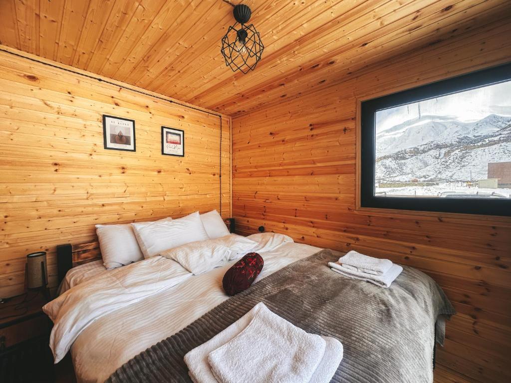 a bedroom with a bed in a wooden room at Wildwood Kazbegi in Stepantsminda