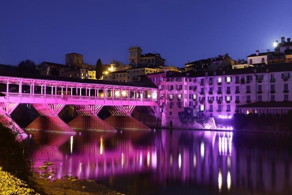 a bridge over a river at night with purple lights at HEATHER'S HOME 108 - Appartamento vista mozzafiato in Bassano del Grappa
