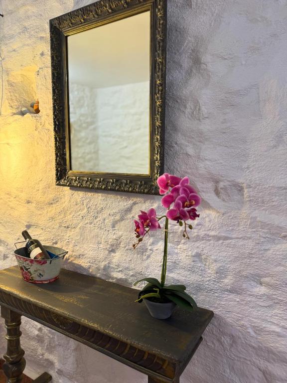 a flower in a vase on a table with a mirror at O Mylos in Ermoupoli
