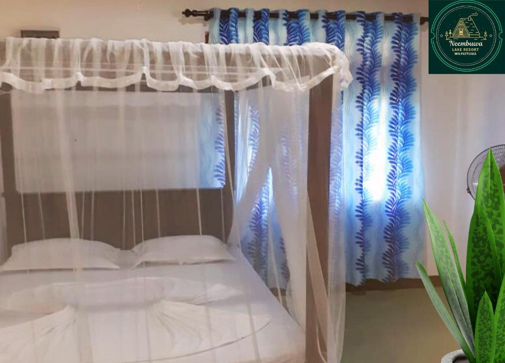 a bedroom with a canopy bed with white curtains at Neembuva Resort in Pahala Maragahawewa