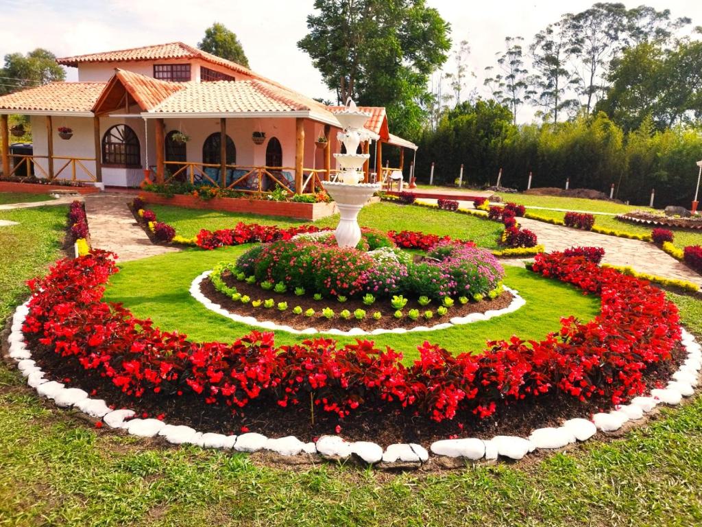 un jardín con flores rojas frente a una casa en HERMOSA CABAÑA VILLA JULIA MESA DE LOS SANTOS, en Piedecuesta