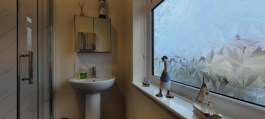 a bathroom with a sink and a window with a statue at Room 3 Penrhyn drive in Llandrillo-yn-Rhôs