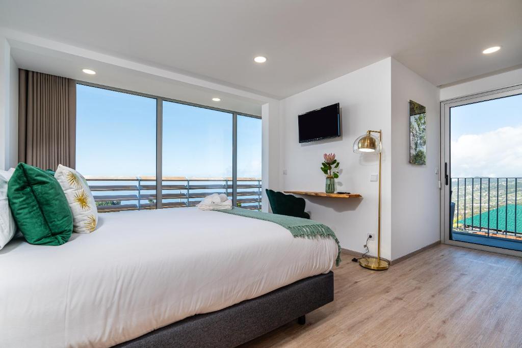 ein Schlafzimmer mit großem Bett und großen Fenstern in der Unterkunft Bella Vista (Heated Pool & Private Parking) in Arco da Calheta