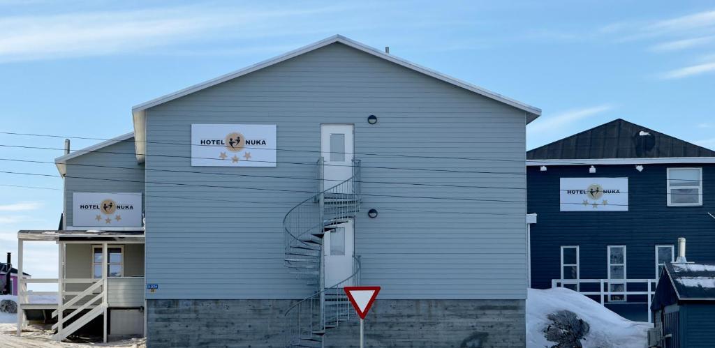 ein graues Gebäude mit zwei Fenstern und einem Brandzeichen in der Unterkunft Hotel Nuka in Ilulissat