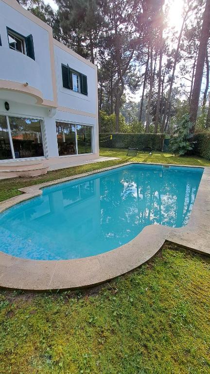 a large blue swimming pool in front of a house at Golf, Pool and Beach Aroeira Villa in Aroeira