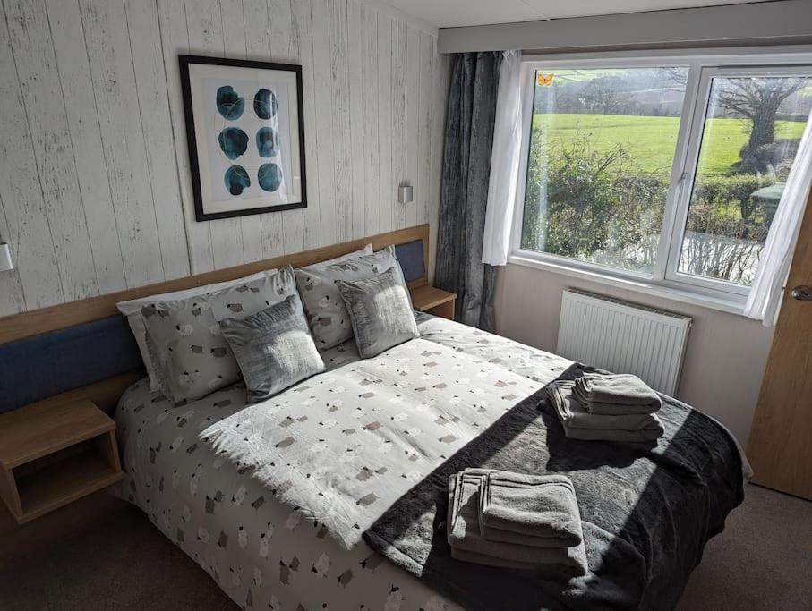 a bedroom with a bed with a comforter and a window at Sarn Y Glyn in Mid Wales Cambrian Mountains near Llanidloes Powys in Caersws