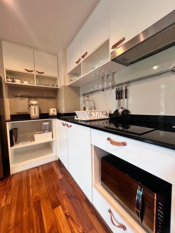 a kitchen with white cabinets and a black stove top oven at The Title Rawai: Beachfront condotel in Rawai Beach