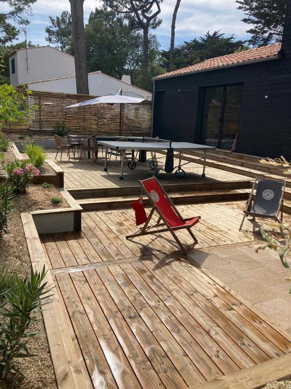 une terrasse en bois avec une table de ping-pong et des chaises dans l'établissement Joyau au cœur de la forêt, à La Guérinière