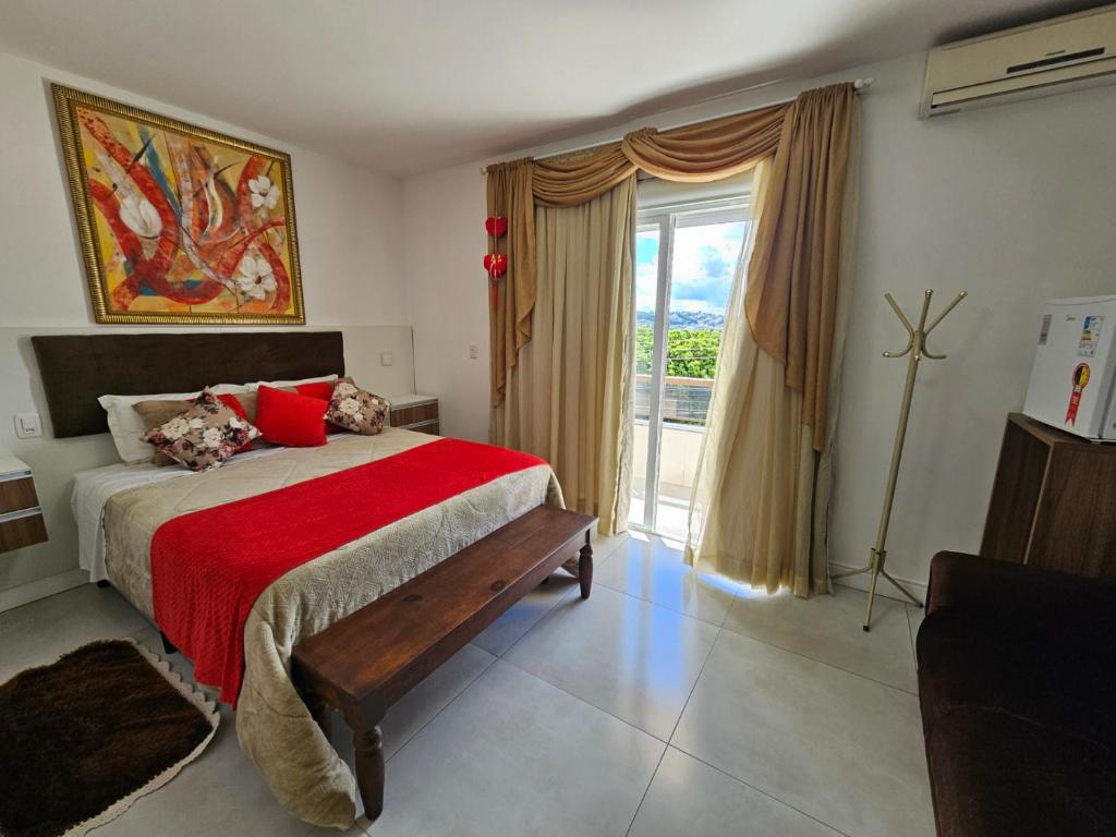 um quarto com uma cama com um cobertor vermelho e uma janela em Pousada Lugama em Bento Gonçalves