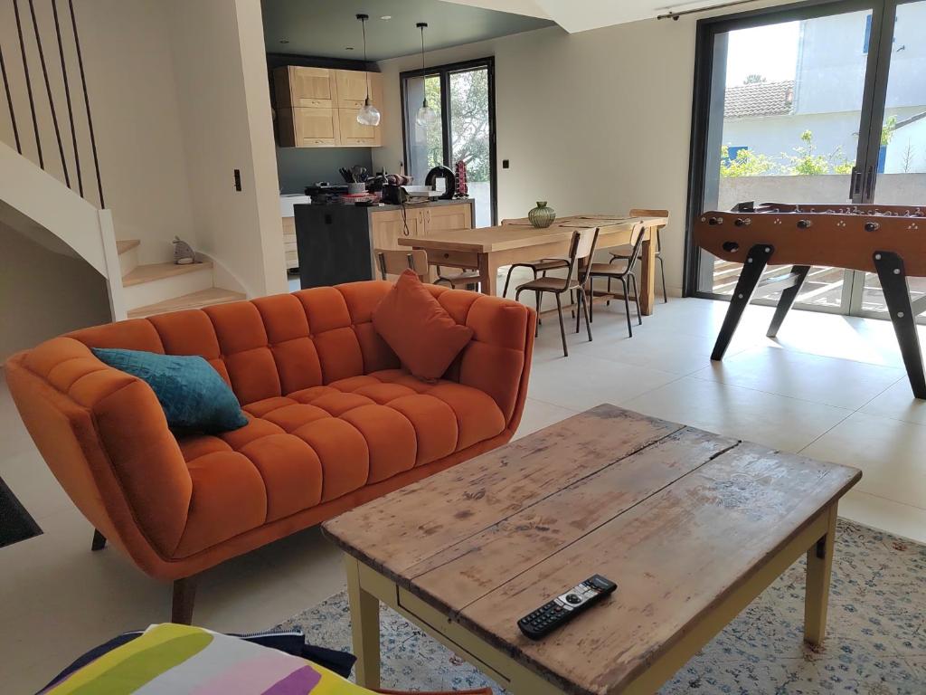 a living room with an orange couch and a table at Joyau au cœur de la forêt in La Guérinière