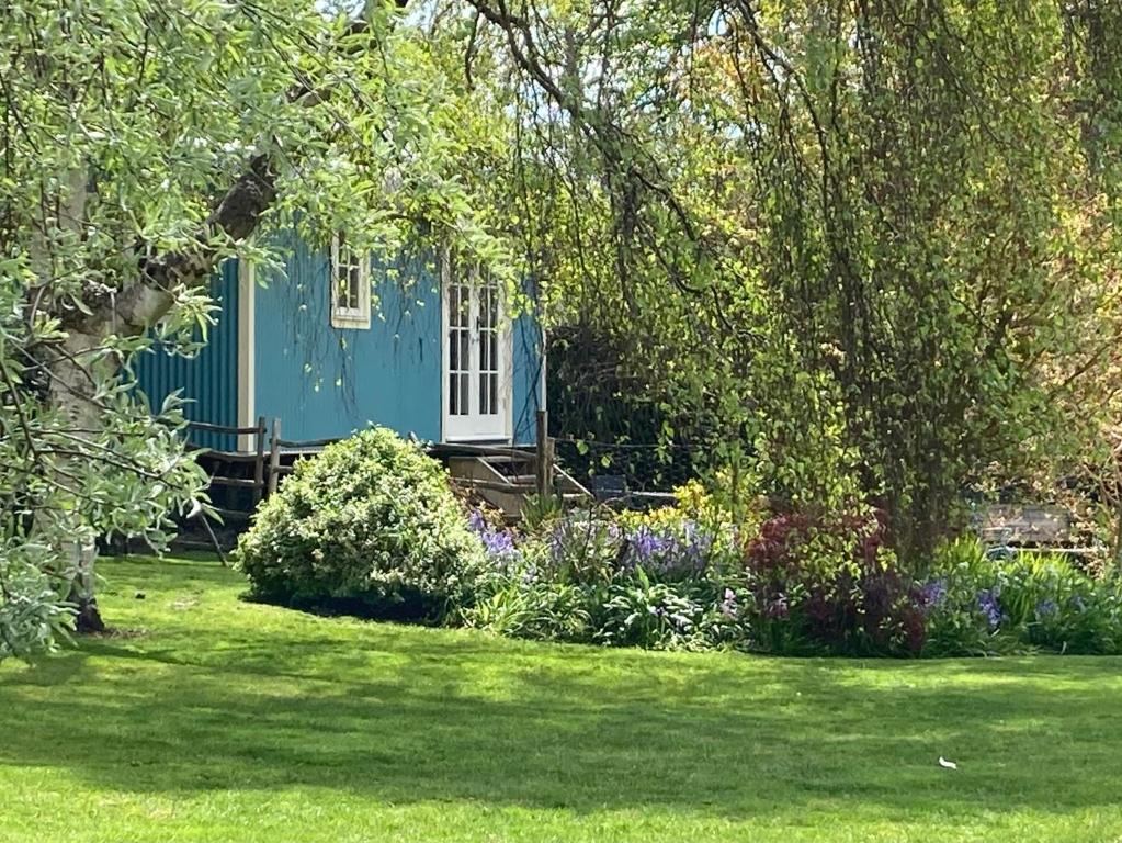 a blue house in the middle of a yard at The Bailey Shepherd's Hut and Holiday Cottage in Skipton