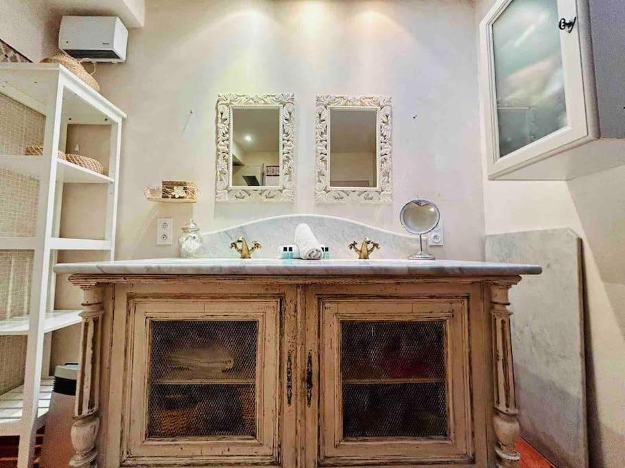 ein Badezimmer mit einer Badewanne und einem Waschbecken mit Spiegeln in der Unterkunft « Côté jardin » Central/Piscine/Jacuzzi/Parking in Carcassonne