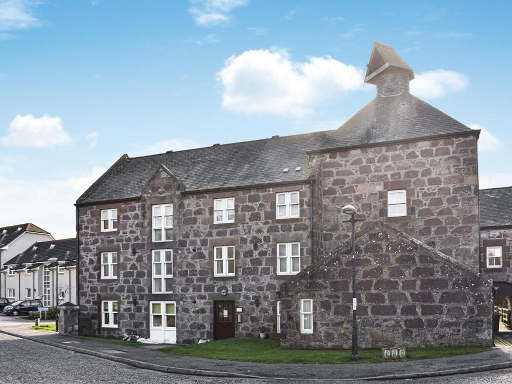 an old stone building on the side of a street at Cowie Mill Apartment in Stonehaven