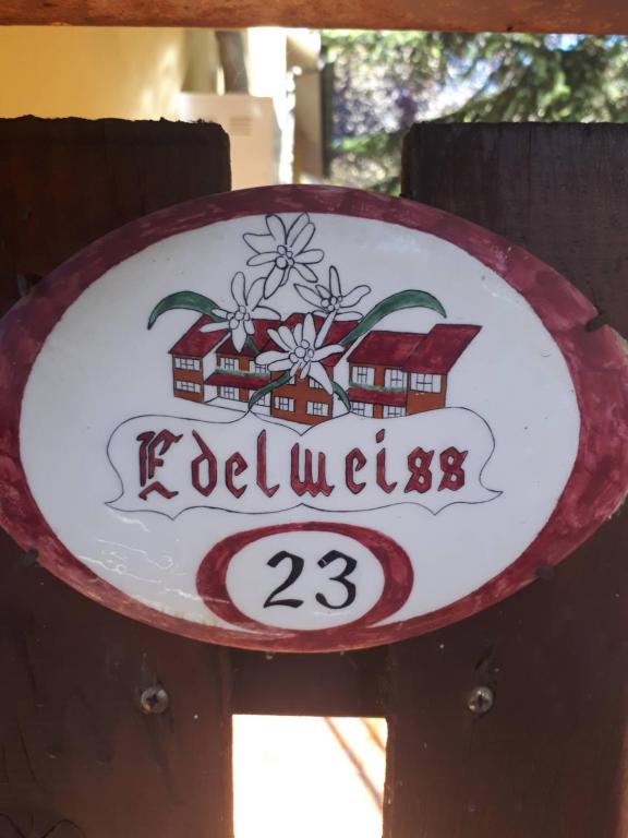 a sign on a wooden fence with a house at RESIDENCE EDELWEISS in Spogna