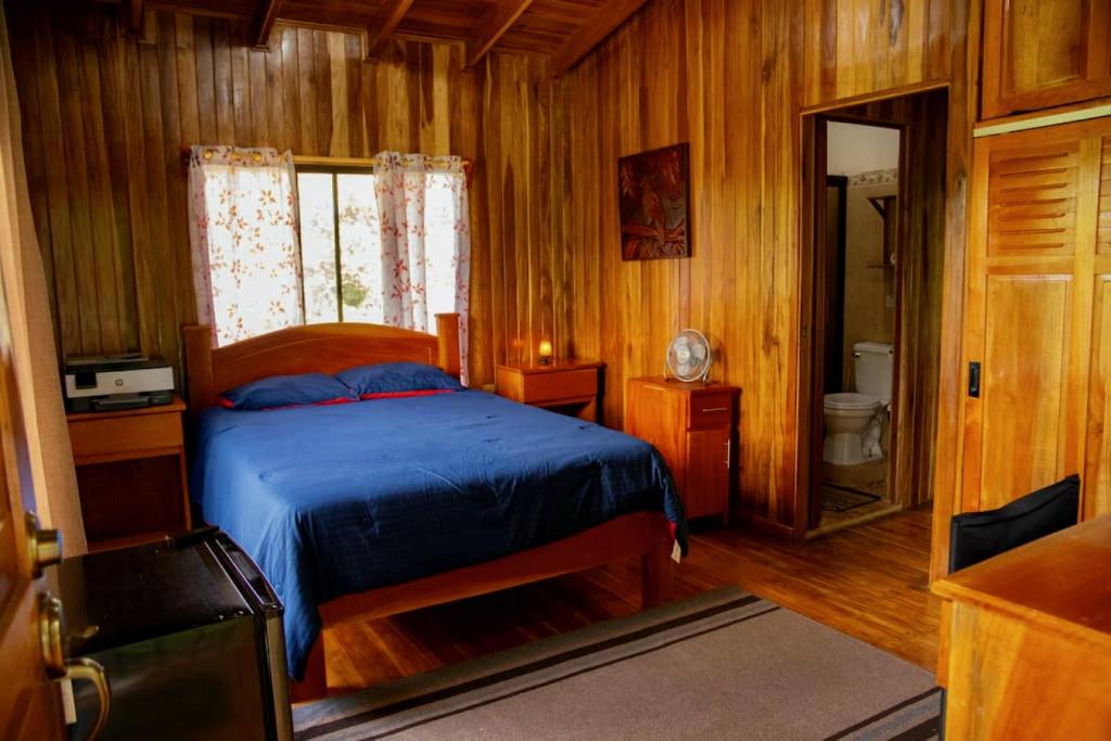 - une chambre en bois avec un lit bleu dans l'établissement Rancho Costafalo Eco-Tourism Farm, à Quebrada Grande