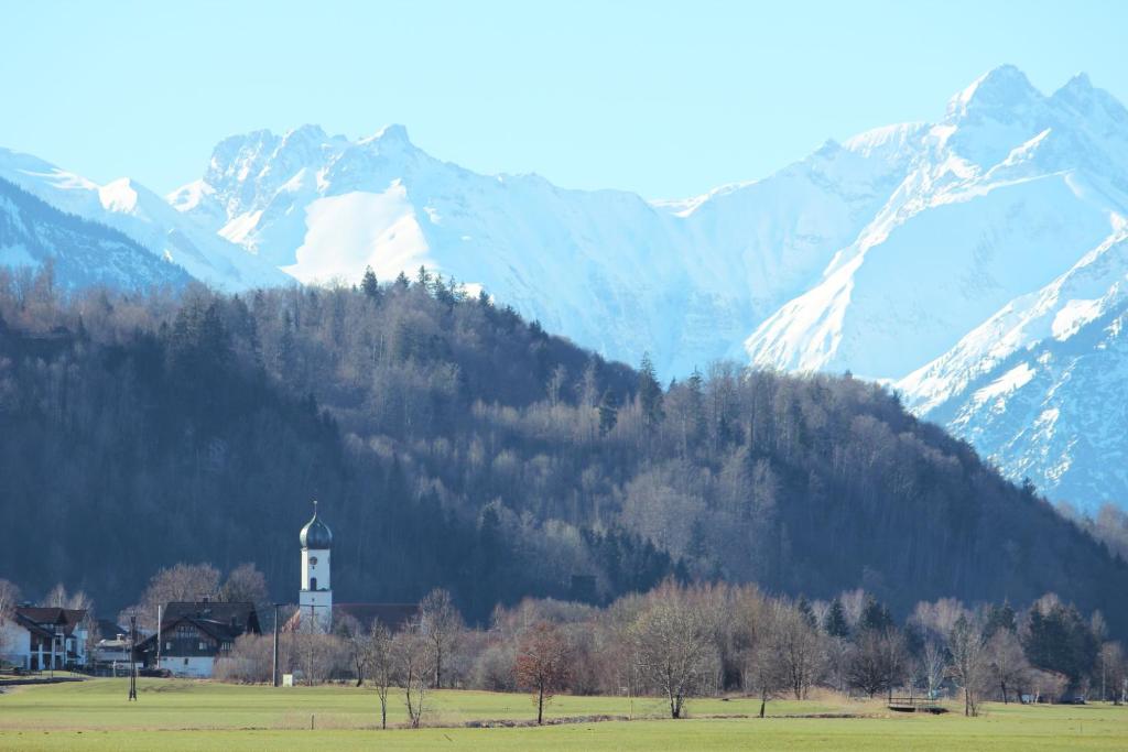 a church in a field with mountains in the background at Ferienwohung Familie Schröttle in Sonthofen