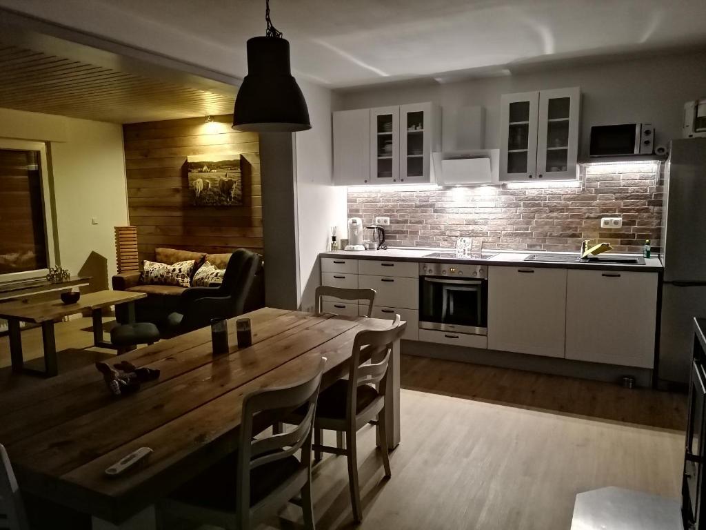 a kitchen and living room with a wooden table and a dining room at Ferienwohnung Waldblick in Bad Essen
