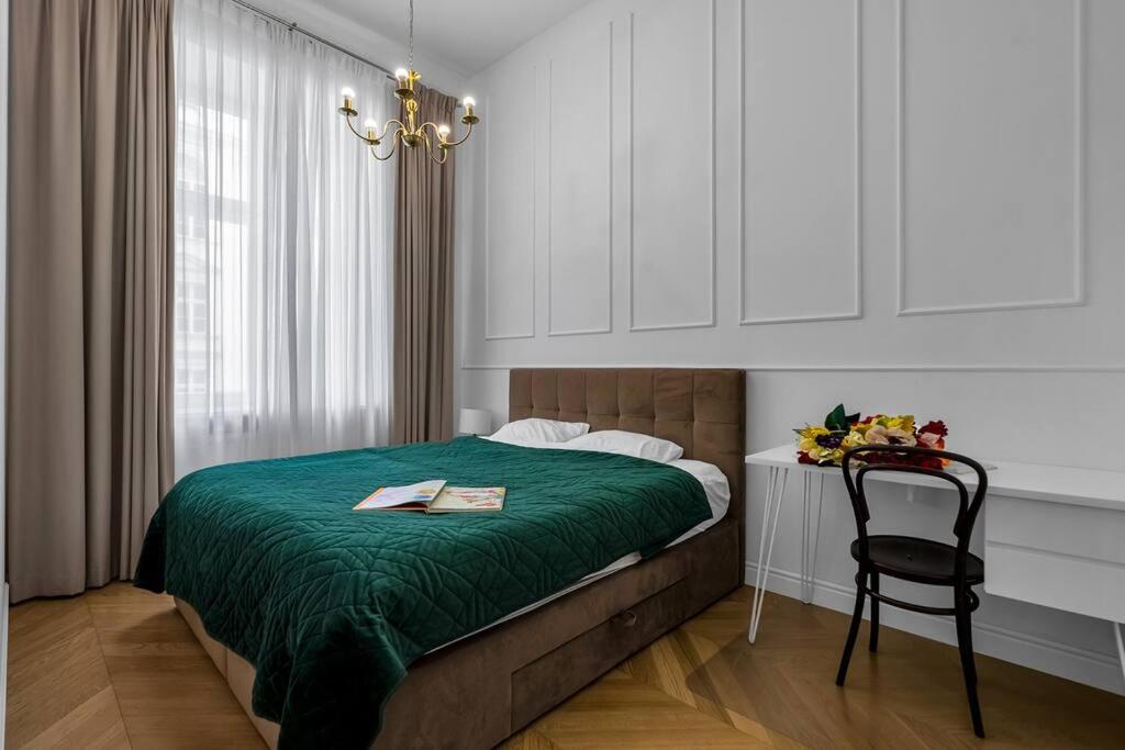 a bedroom with a bed with a green blanket and a chair at Luxury Apartment next to Koszykowa Street in Warsaw