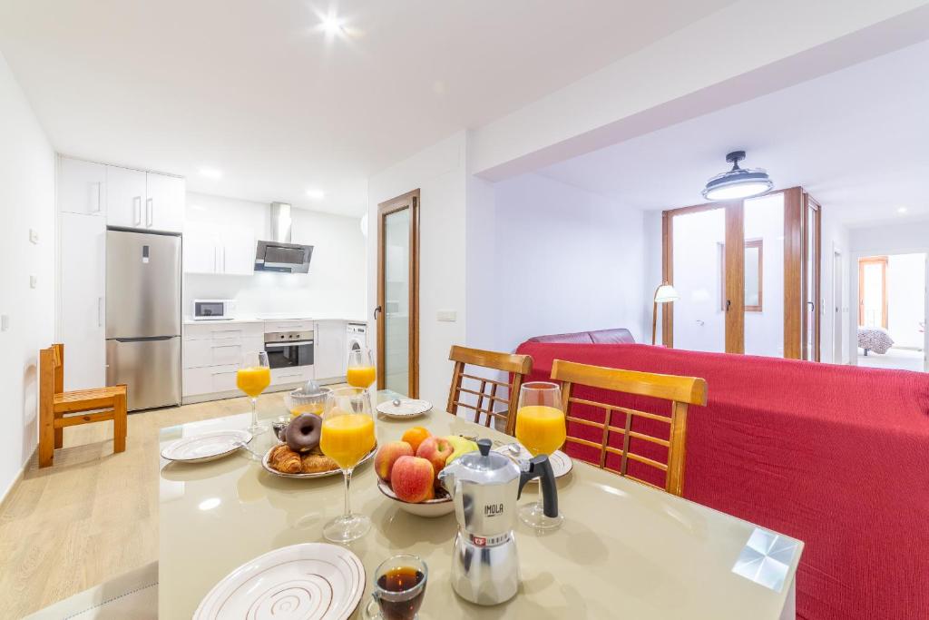 sala de estar y cocina con mesa con comida y bebida en Casa Gómez, parking gratuito en Pleno Centro, en Almería