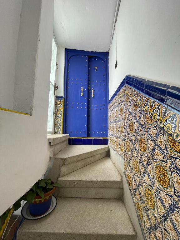 a hallway with a blue door and stairs at Dar Mora in Tangier