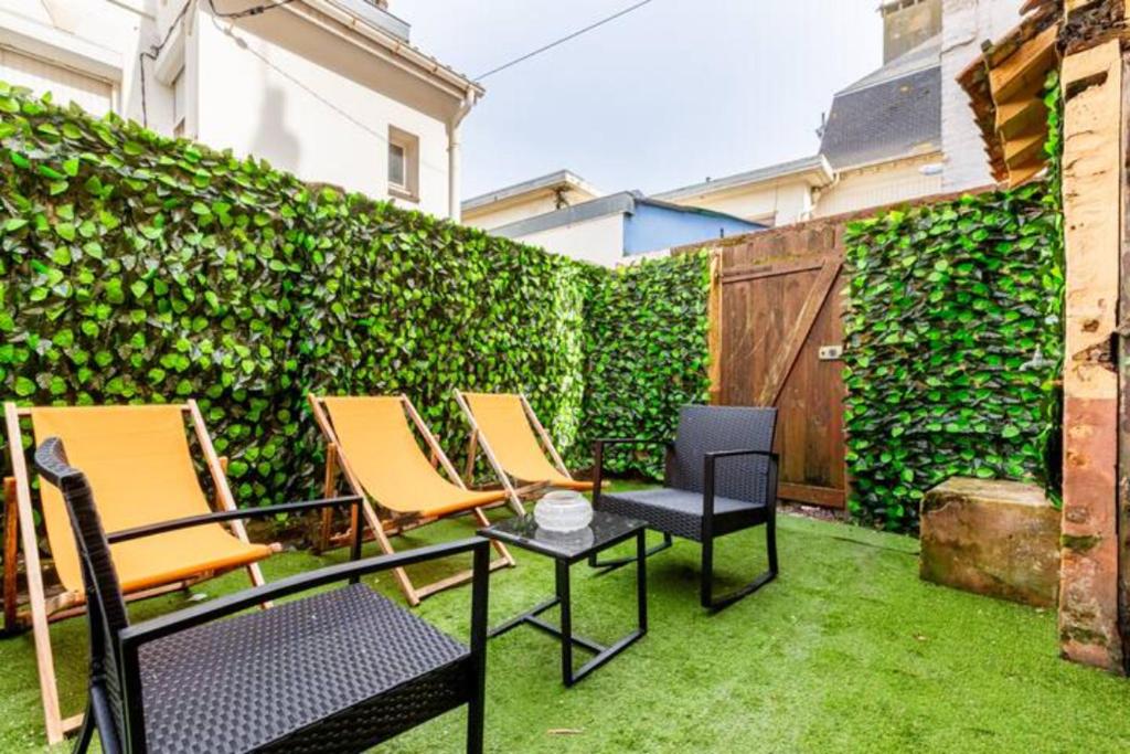 un patio con sillas y una mesa frente a un seto verde en ++++ CENTRAL charmant 70m2 avec balcon, mer à 200 m et rue piétonne à 300 m ++++, en Berck-sur-Mer