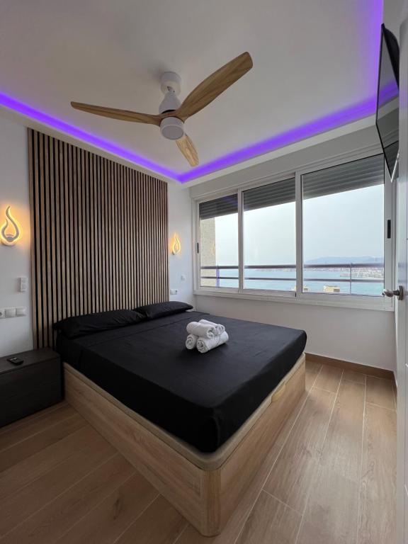 1 dormitorio con 1 cama grande y ventilador de techo en Hany apartment Tropic mar 18-C, en Benidorm