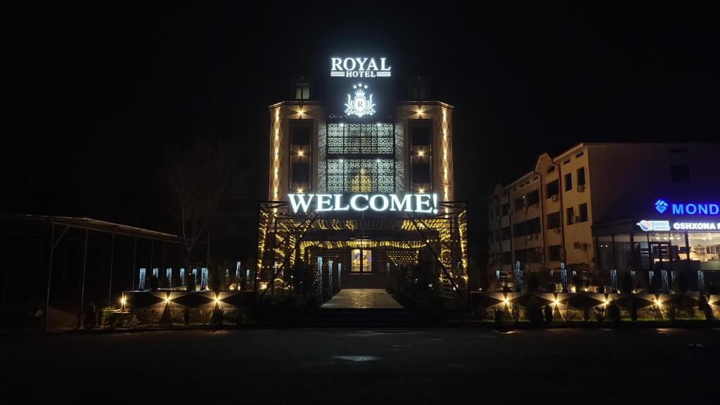 ein Gebäude mit einem Willkommensschild darauf in der Nacht in der Unterkunft Royal Hotel in Navoiy