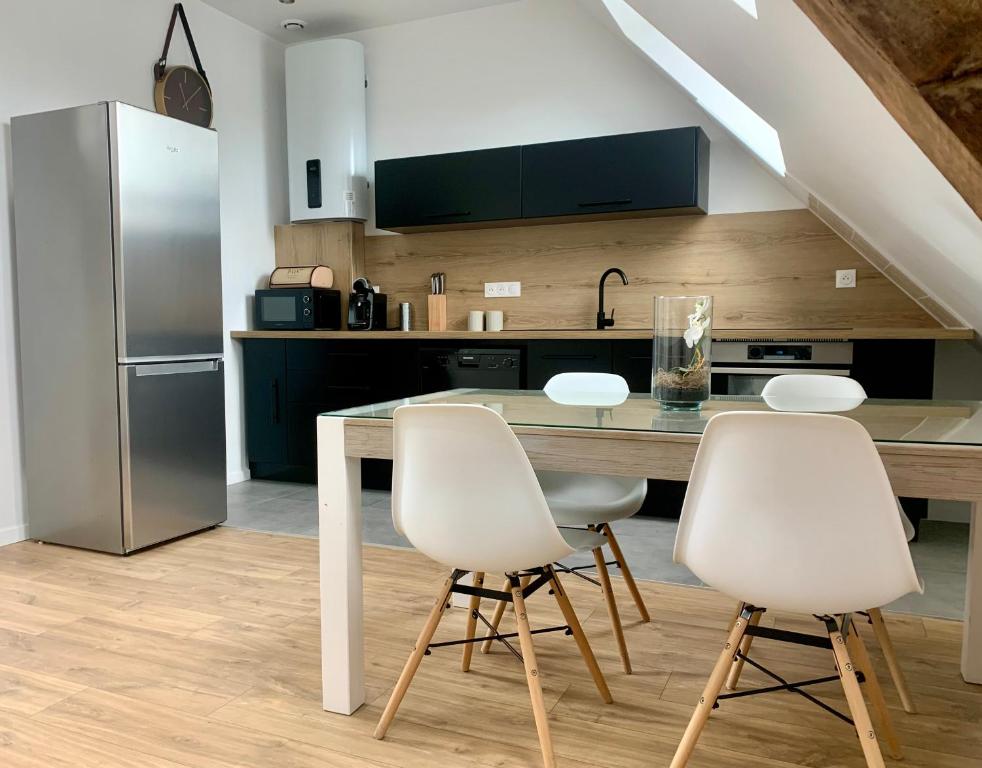 a kitchen with a table and four white chairs at Appartement Cosy, Résidence de l’Ecluse in Arques