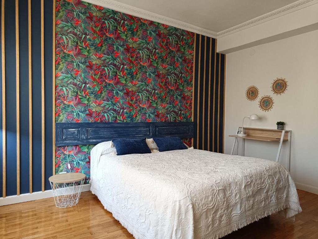a bedroom with a bed with a large painting on the wall at Apartamento céntrico La Morada Santanderina in Santander