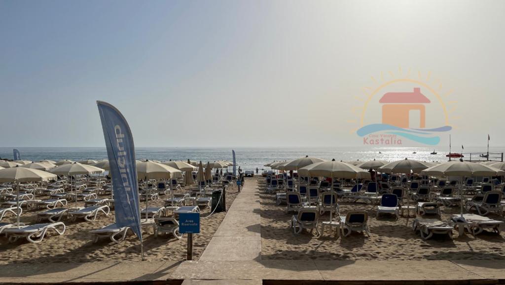 una playa con un montón de sillas y sombrillas en casavacanzekastalia en Ragusa