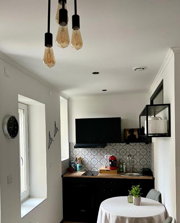 Il comprend une cuisine avec une table et une télévision murale. dans l'établissement sainte Cécile 3: studio élégant idéalement situé, à Vichy