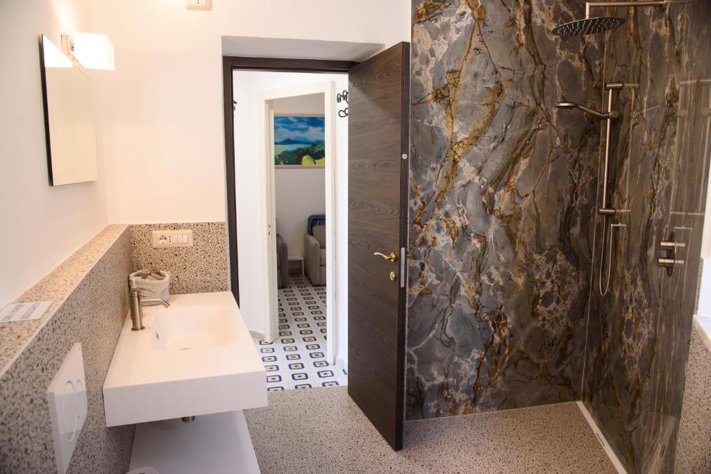 La salle de bains est pourvue d'un lavabo et d'une douche. dans l'établissement Il Giardino Di Tatiana Rooms & Breakfast, à La Maddalena