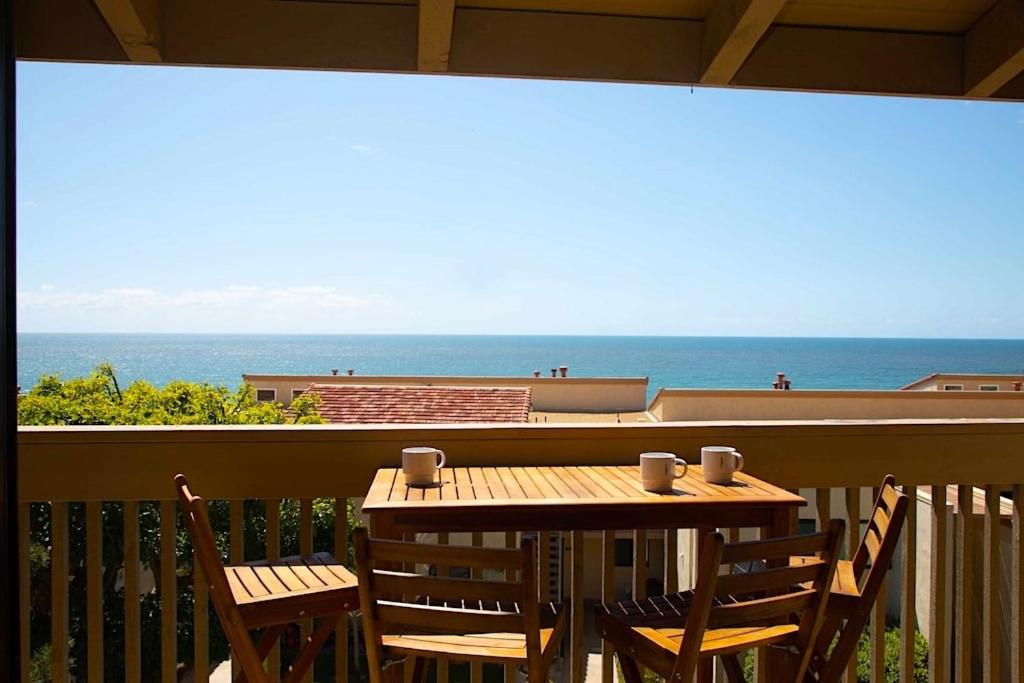 a wooden table and chairs on a balcony with the ocean at Solana Beach Sol condo in Solana Beach
