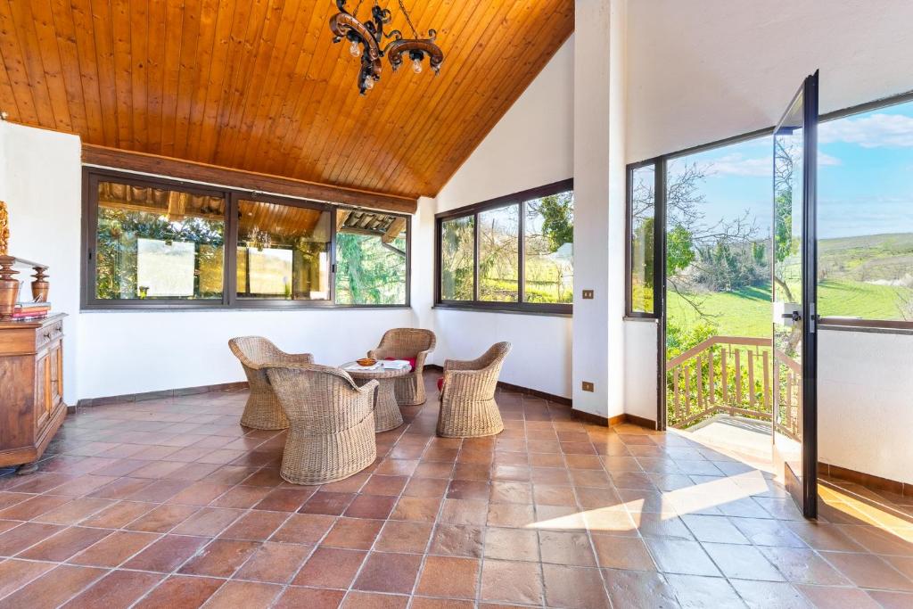 a living room with a table and chairs and windows at Casa Daniel - casa con giardino in Magliano Alfieri