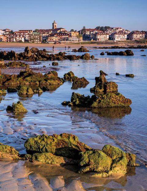 a group of rocks in the water on a beach at Playa Y Cañas in Noja