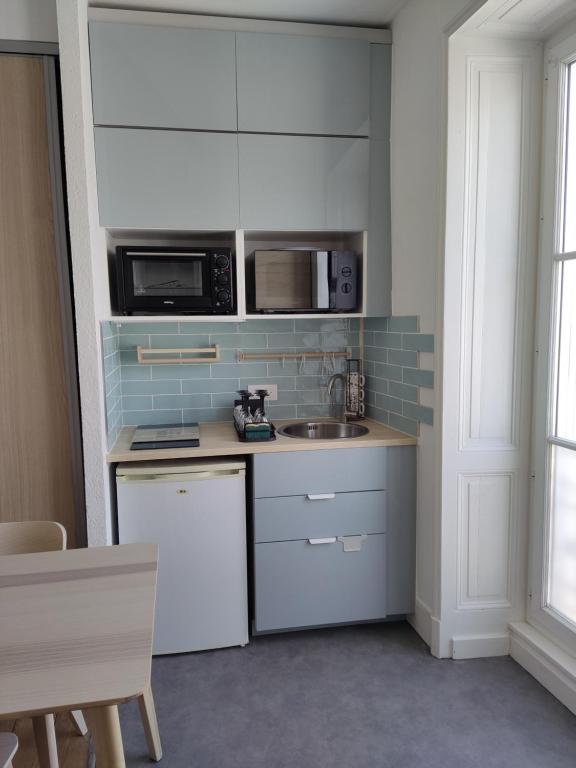 une cuisine avec un évier et un micro-ondes dans l'établissement studio hyper centre la rochelle, à La Rochelle