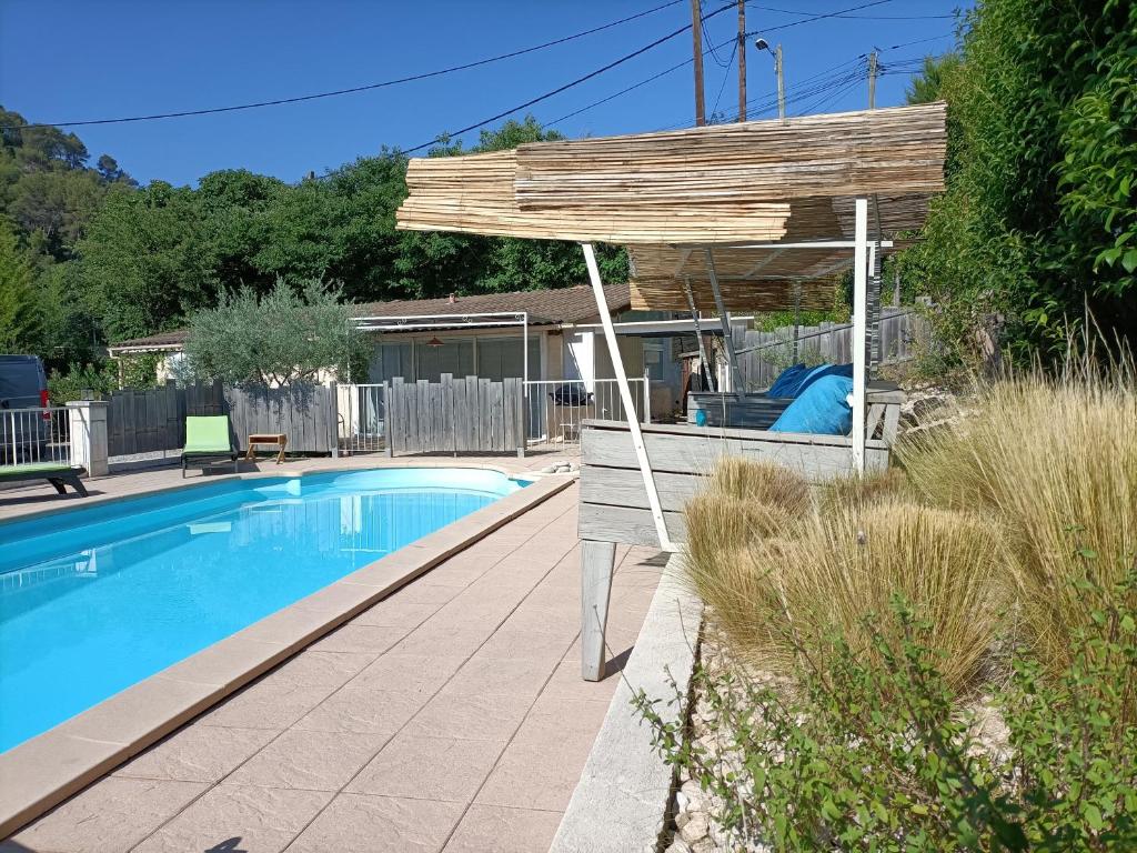 a wooden pergola sitting next to a swimming pool at gîte en provence in Peypin