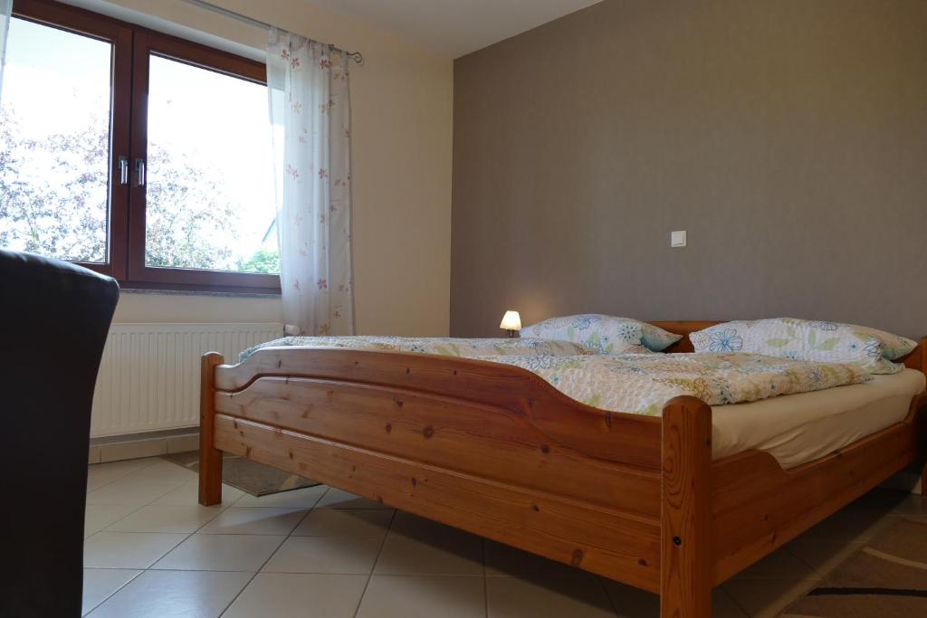 1 dormitorio con cama de madera y ventana en Ferienwohnung Basche, en Oberzissen