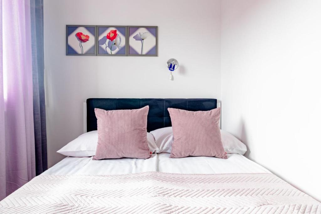 a bedroom with a bed with pink and white pillows at Willa Bliźniak 2 - 300m od Plaży Śniadanie W Cenie Pobytu in Karwia