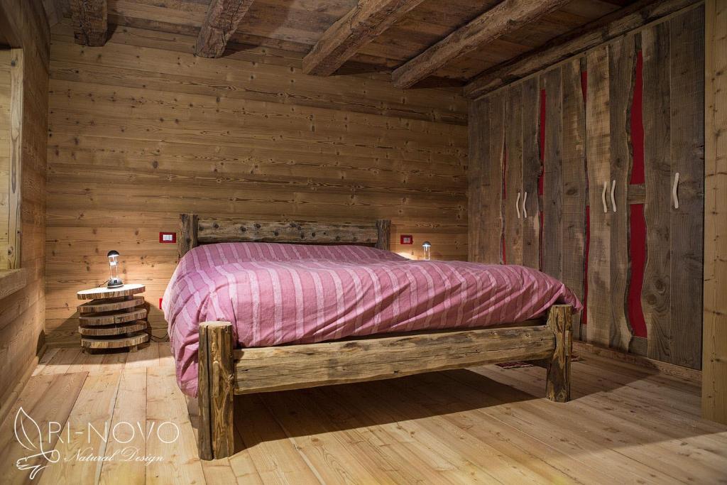 sypialnia z łóżkiem w drewnianym domku w obiekcie Chalet Lagorai w mieście Roncegno