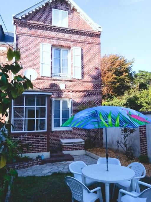 une table avec un parasol devant une maison dans l'établissement La maison de Cilou, à Étretat