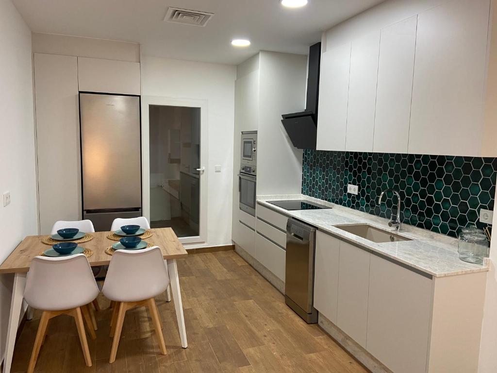 a kitchen with white cabinets and a wooden table and chairs at Apartament centre casaPat in Xàtiva