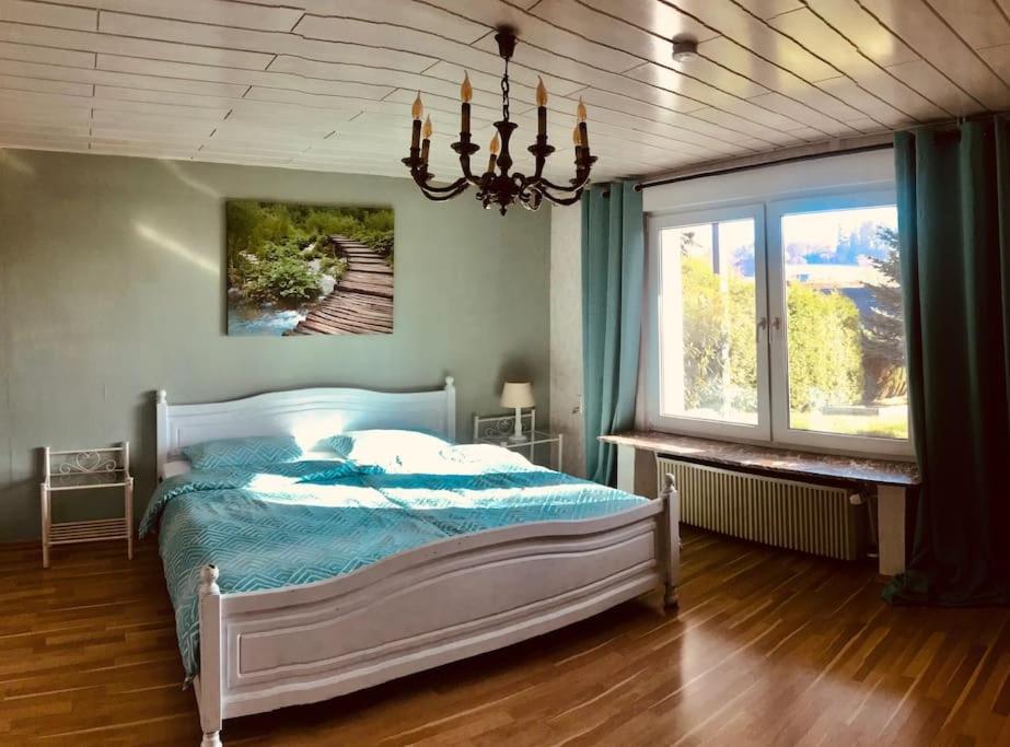 a bedroom with a bed and a chandelier at Urlaub im Grünen - Ferienwohnung EG im Brunnenhof in Reichshof 