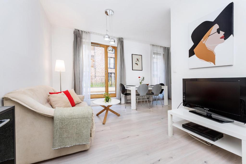 uma sala de estar com uma televisão de ecrã plano e um sofá em Old Town Apartment Browar Lubicz Krakow em Cracóvia