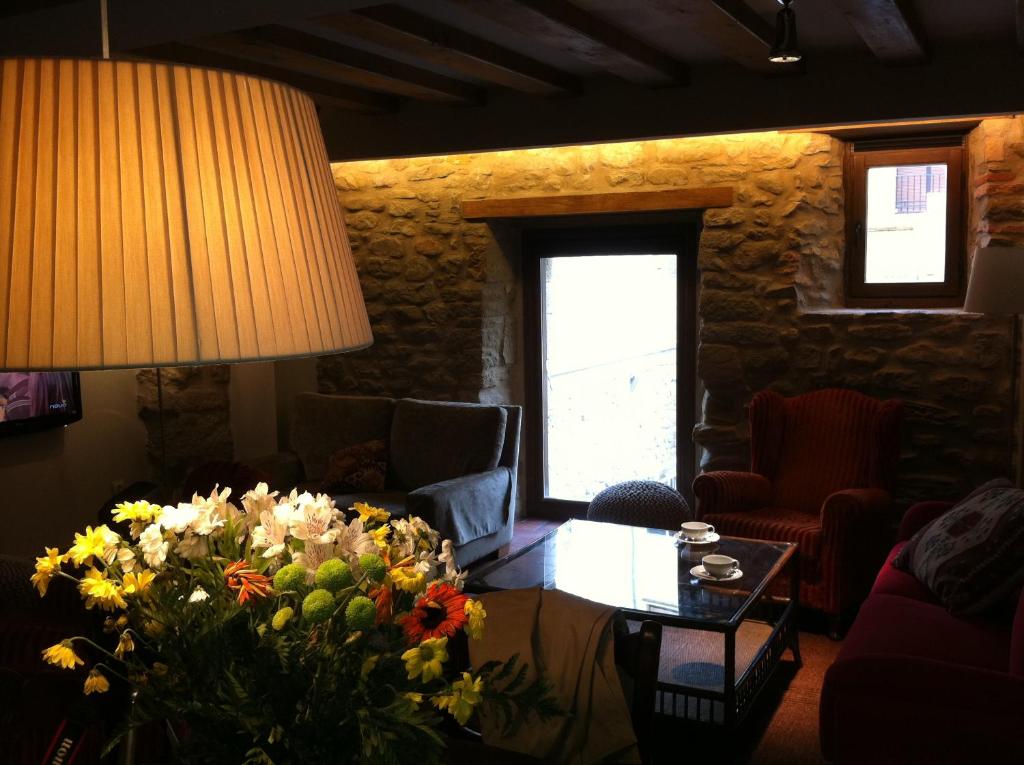 a living room with a table with a bouquet of flowers at Hotel El Cerco in Puente la Reina