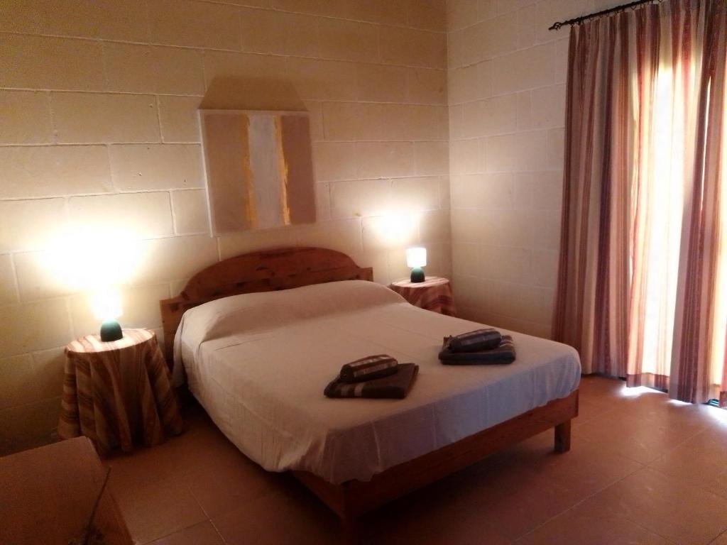a bedroom with a bed with two robes on it at Bed and Breakfast Dar Tal-Lumija in Għajnsielem