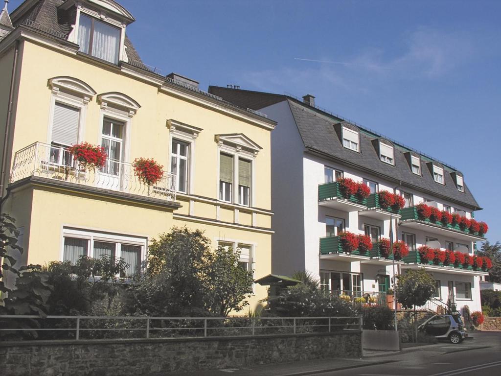 ein gelbes Gebäude mit Blumenkästen auf den Balkonen in der Unterkunft Gästehaus Vis-A-Vis in Rüdesheim am Rhein